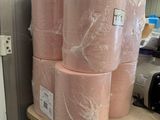 plusieurs rouleaux de papier de soie rose posés sur une étagère dans une pièce