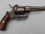 un vieux revolver avec une poignée en bois sur une surface blanche
