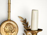 a gold wall sconce with a candle on it