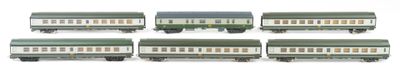 six green and white train cars are lined up on a white surface