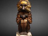 an image of a wooden statue of a man with a bird on his head