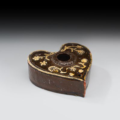 une vieille boîte en forme de cœur posée sur une surface blanche