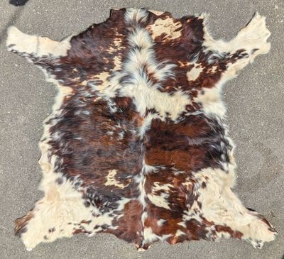 tapis en peau de vache marron et blanche posé sur un sol en béton