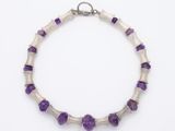 un gros plan d'un bracelet orné de perles violettes sur fond blanc