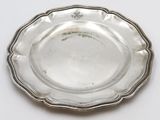 an antique silver plate on a white surface with a silver rim