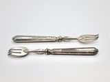 pair of silver plated utensils on a white surface