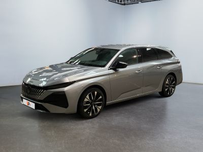 La voiture argentée est garée dans une grande pièce aux murs blancs.