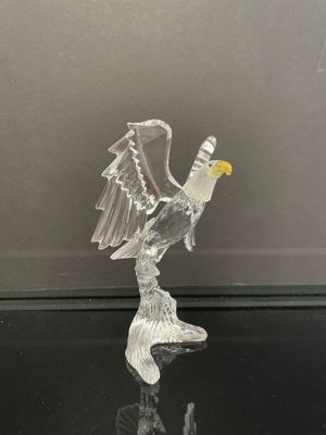 figurine en verre représentant un oiseau aux ailes déployées, posée sur un fond noir