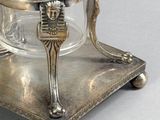 a silver plate with a glass on it on a stand