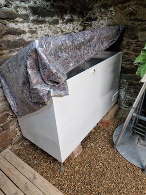 une boîte blanche recouverte d'une couverture, posée près d'une cheminée