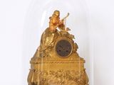 une horloge en or sous un dôme de verre sur une table