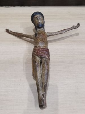 une petite statue représentant une personne sur une croix, posée sur une table