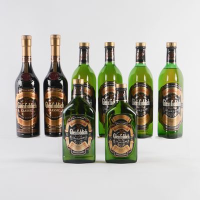 six bouteilles de whisky sont alignées sur une surface blanche