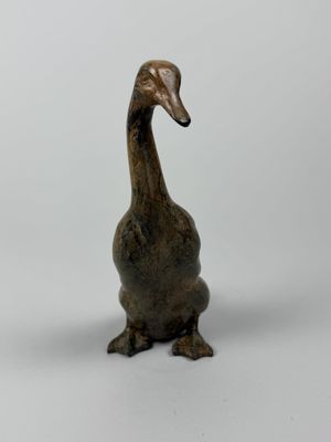 une petite statue représentant un canard posée sur une surface blanche