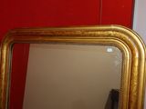 a mirror with a gold frame on a red wall