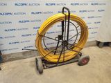 a cart with a yellow hose on it in front of a wall