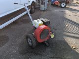 a small lawn mower that is sitting in the parking lot