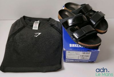 des sandales noires Birkenstock et un t-shirt posés sur une boîte