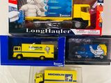 Trois camions miniatures sont exposés dans une vitrine posée sur une surface blanche.
