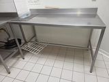 a stainless steel work table in the corner of a kitchen