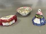 trois petites figurines en céramique représentant des femmes et un bol rempli de fleurs