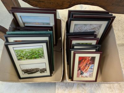 six framed pictures in a cardboard box on a table