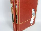 two red books sitting on top of each other on a white surface