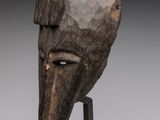 gros plan d'un masque en bois sur un support métallique