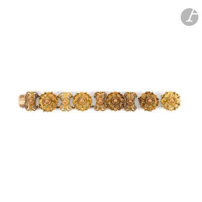 a close up of a gold bracelet with flowers on a white background