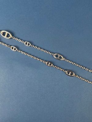 a close up of a pair of silver chain bracelets on a blue background