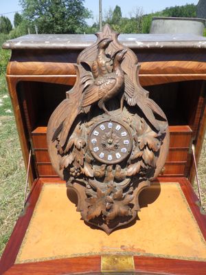 une horloge en bois ornée d'un oiseau, posée dans une boîte