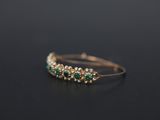 a close up of a gold ring with emerald stones