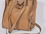 tan leather handbag with handle and strap on white background