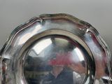 a silver plate that has a reflection of a person in it