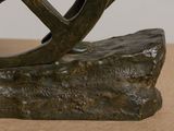 a bronze sculpture of a bird sitting on a rock