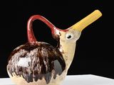 a small vase with a bird on it on a table