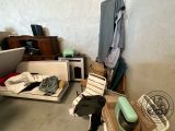 a room with a bed, a microwave, a chair, and other items on the floor