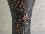 a black vase with red flowers on it on a table