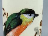 a vase with a bird painted on it sitting on a table