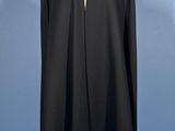 a black cape on a mannequin stand against a blue background