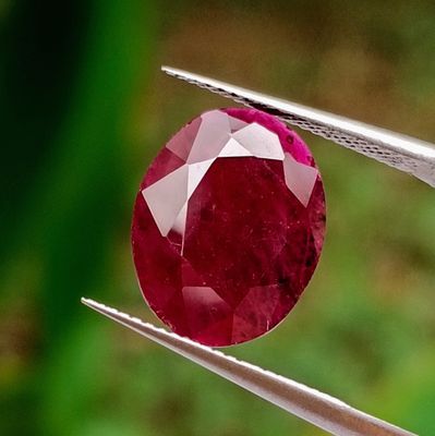 a close up of a red diamond being held by a pair of pliers