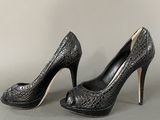 pair of women ' s black high heeled shoes on a gray surface