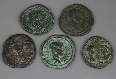 six ancient roman coins are shown in a row on a white surface