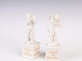 pair of white figurines of cherensils on pedestals