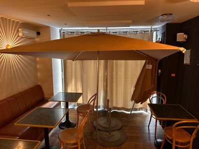 tables and chairs in a restaurant with an umbrella over them