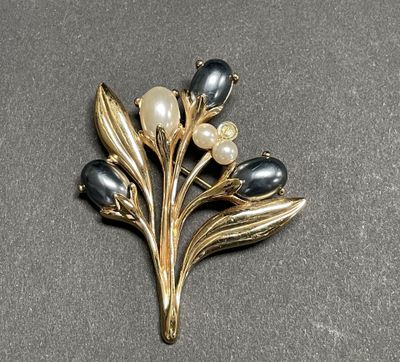 an image of a brooch with pearls and leaves