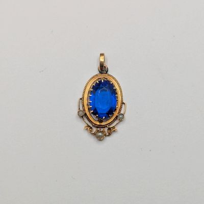 un gros plan d'un pendentif en pierre bleue posé sur une surface blanche
