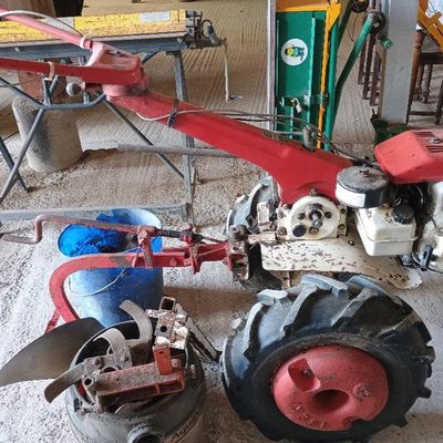 un petit tracteur rouge auquel est attelée une charrue rouge