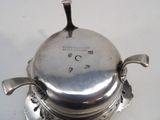a silver plate with a lid that has a spoon on it