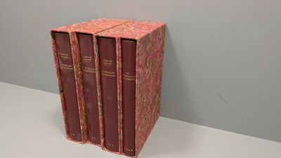 trois livres rouges posés sur une table blanche, près d'un mur gris